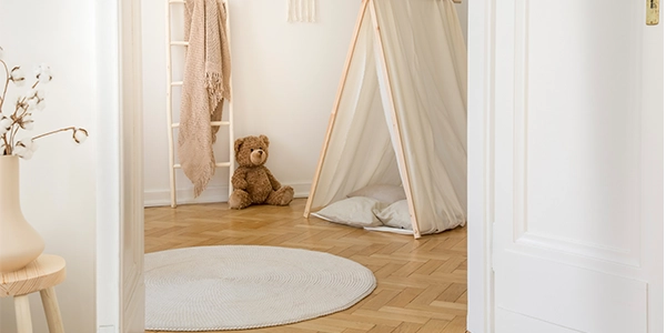 Parkett-online-kaufen-Massivparkett Blick in ein Kinderzimmer mit einem Fischgrat Parkett. Zudem ist eine Leiter, ein Bär und ein Zelt aus Stoff zu sehen.